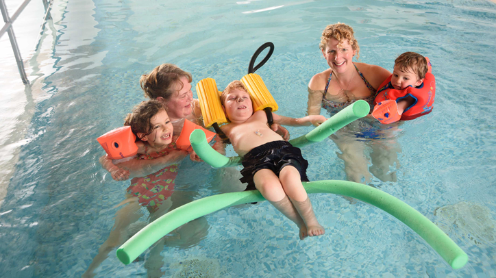 Photo of a family in a swimming pool with floats and armbands