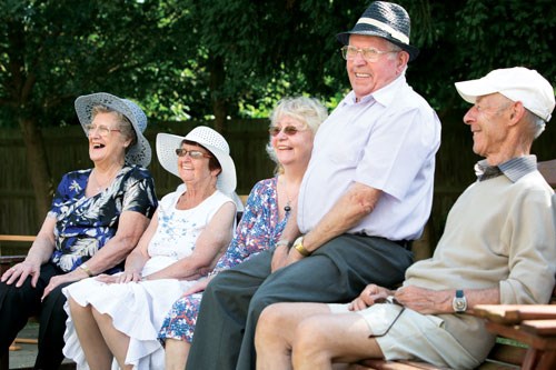 Group of over 50s sat in the sunshine laughing and smiling