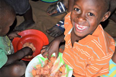 Child smiling with a bowl of food